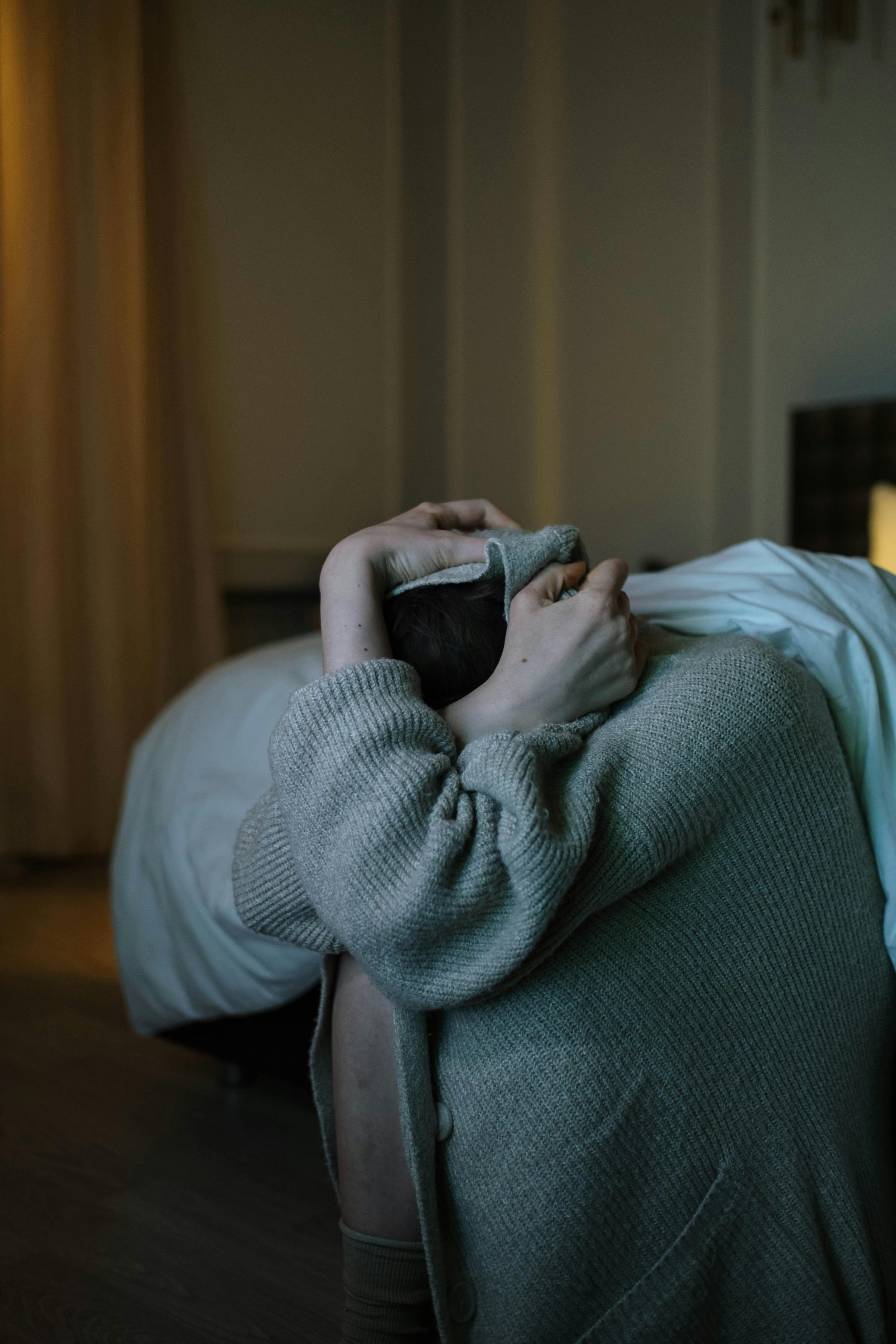 A person wrapped in a blanket, reflecting anxiety and stress in a dimly lit room.